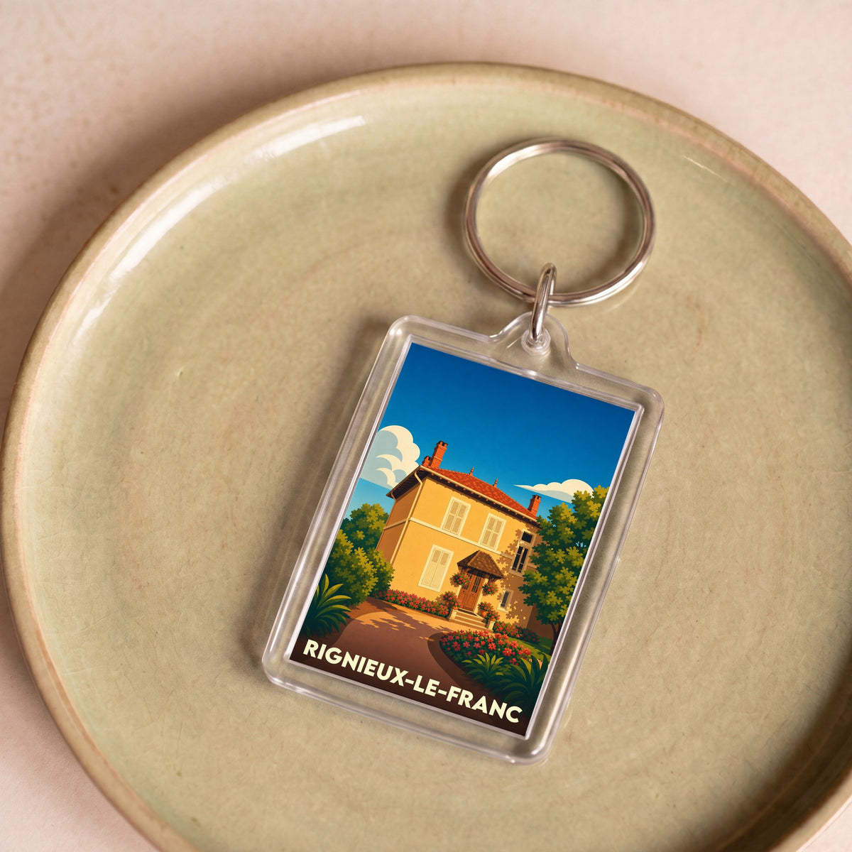 Porte-clés souvenir de la ville de Rignieux-le-Franc avec une illustration stylisée.