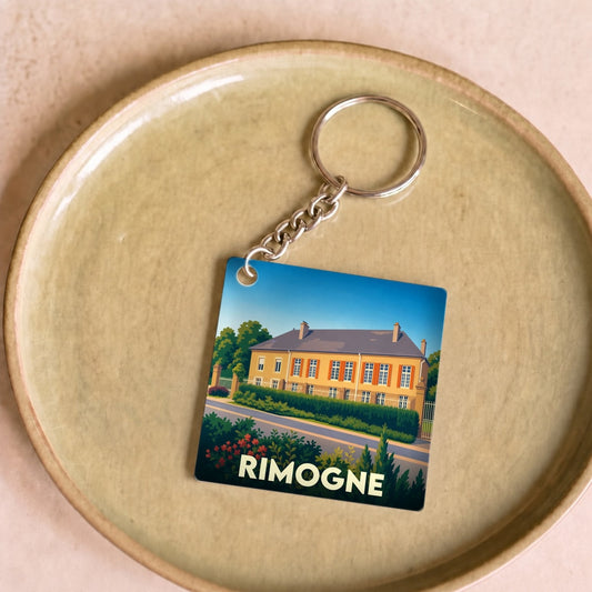 Porte-clés souvenir de la ville de Rimogne avec une illustration stylisée d'une grande demeure.
