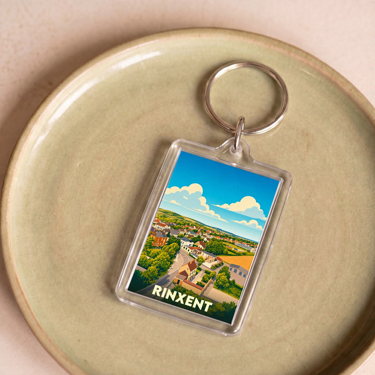 Porte-clés souvenir de la ville de Rinxent avec une illustration stylisée d'un paysage urbain.