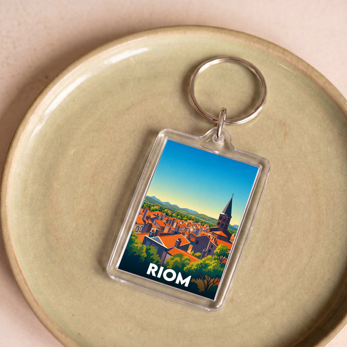 Porte-clés souvenir de la ville de Riom avec une illustration stylisée du paysage urbain.