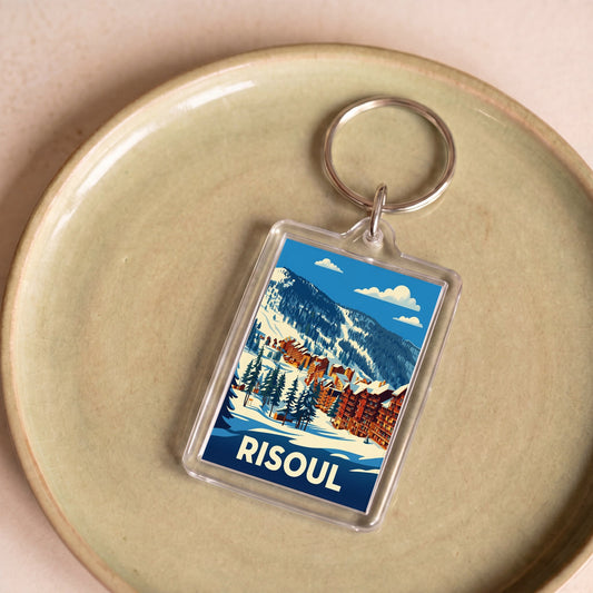 Porte-clés souvenir de la ville de Risoul avec une illustration stylisée de paysages enneigés.