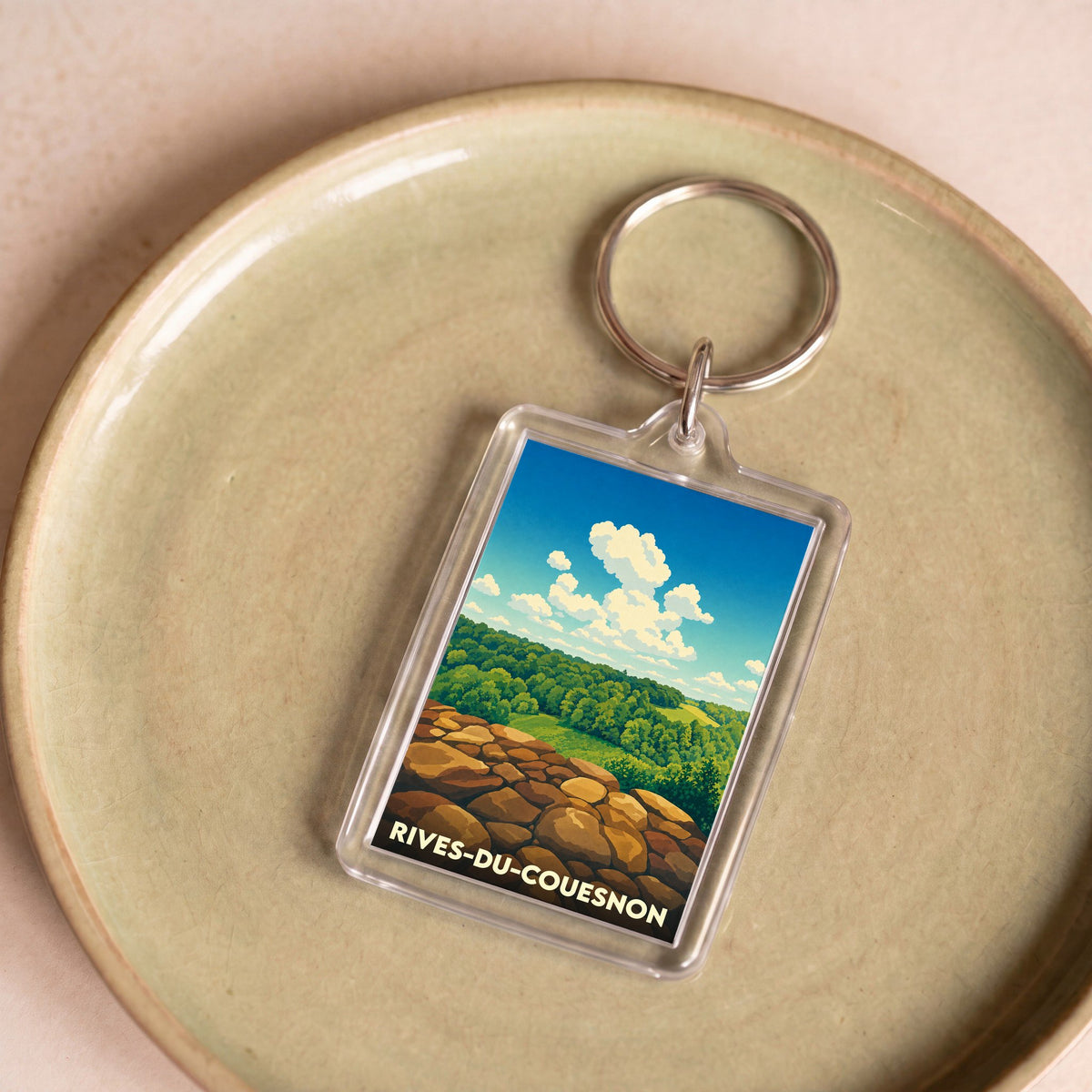 Porte-clés souvenir de la ville de Rives-du-Couesnon avec une illustration stylisée de paysage naturel.