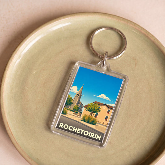 Porte-clés souvenir de la ville de Rochetoirin avec une illustration stylisée d'un paysage urbain.