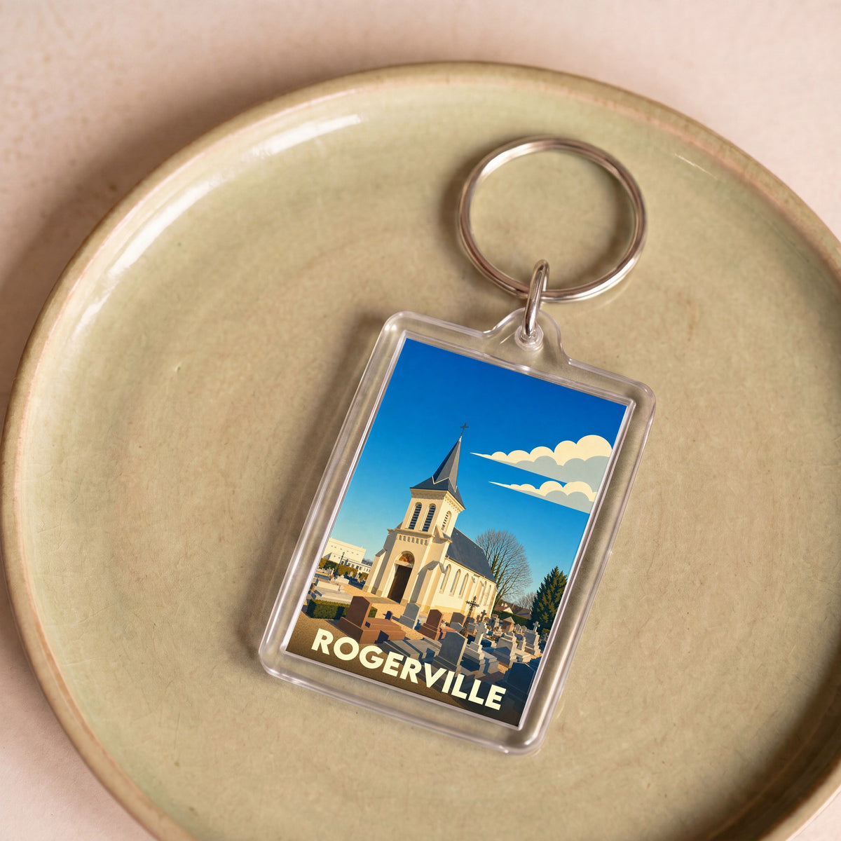 Porte-clés souvenir de la ville de Rogerville avec une illustration stylisée d'une église et de son cimetière.