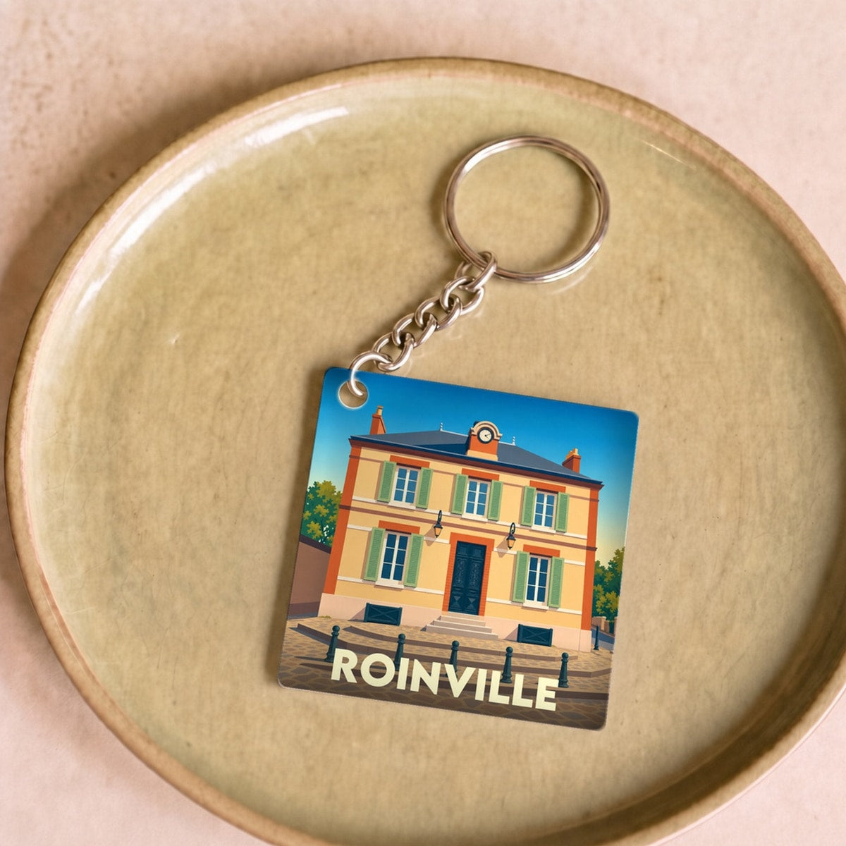 Porte-clés souvenir de la ville de Roinville avec une illustration stylisée de sa mairie.