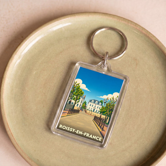 Porte-clés souvenir de la ville de Roissy-en-France avec une illustration stylisée.