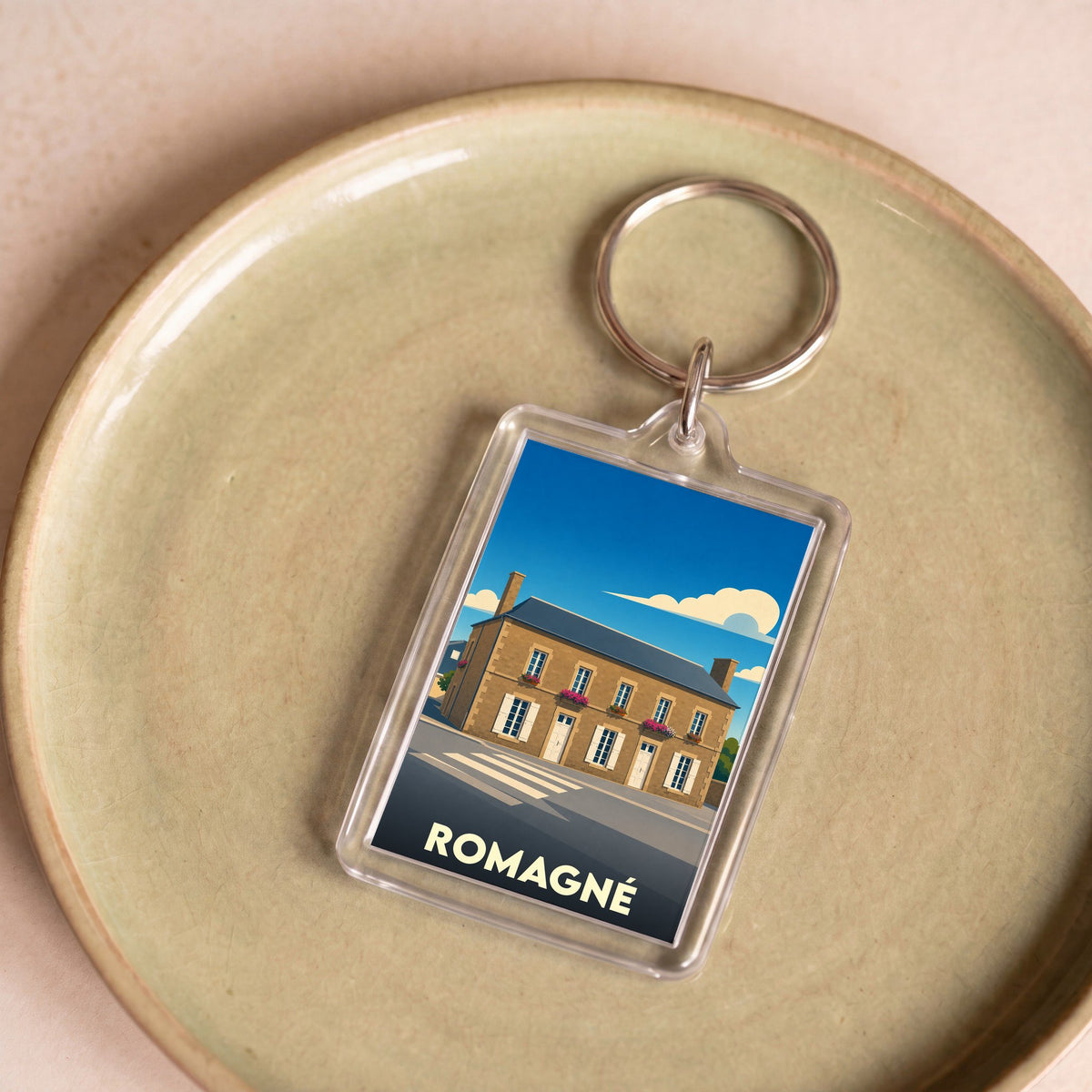 Porte-clés souvenir de la ville de Romagné avec une illustration stylisée d'un bâtiment traditionnel.