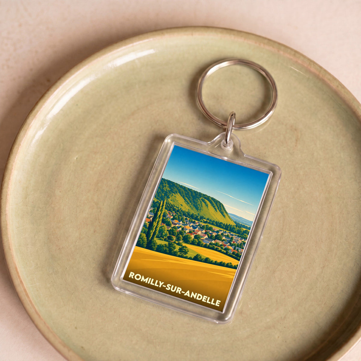 Porte-clés souvenir de la ville de Romilly-sur-Andelle avec une illustration paysagère stylisée.