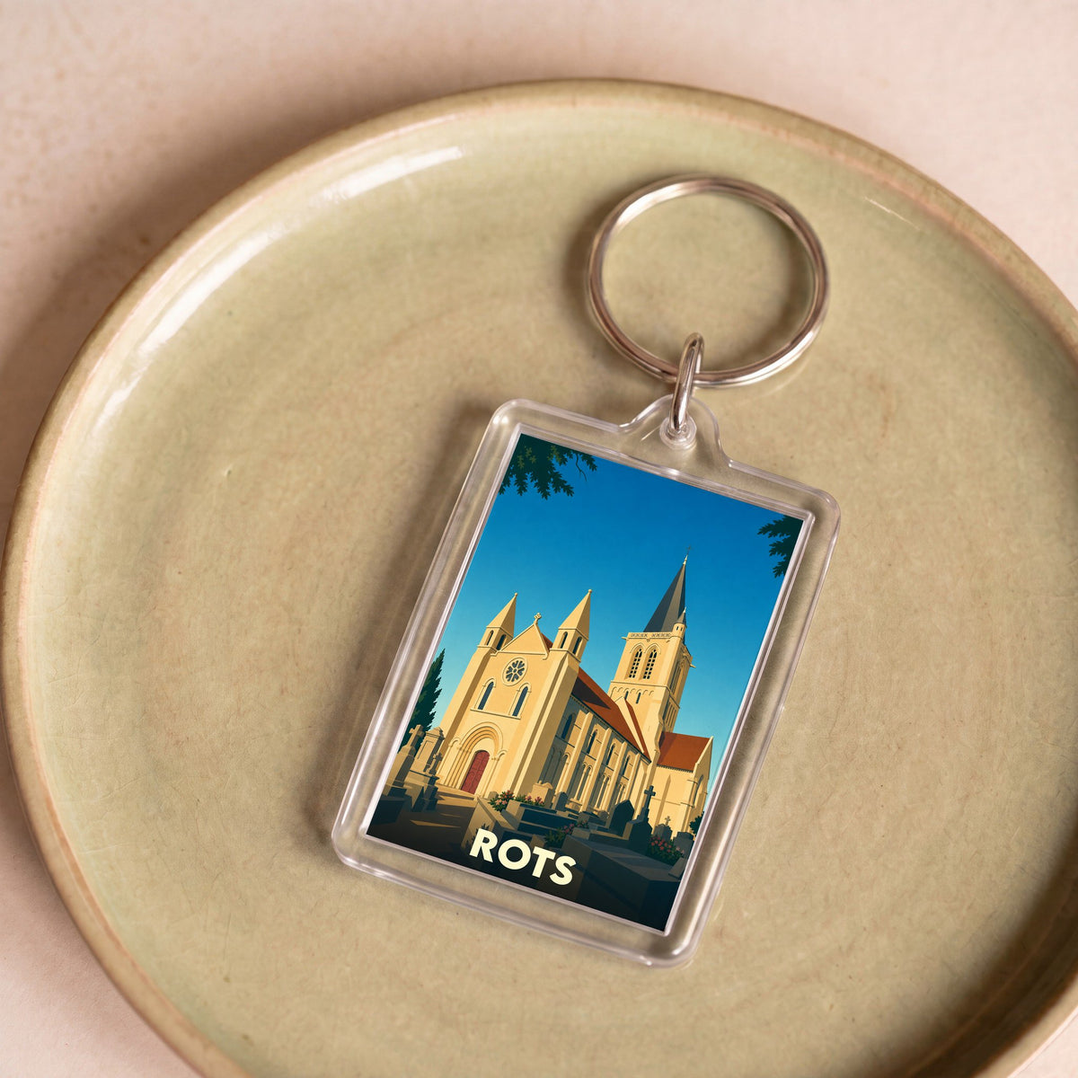 Porte-clés souvenir de la ville de Rots avec une illustration stylisée de son église.