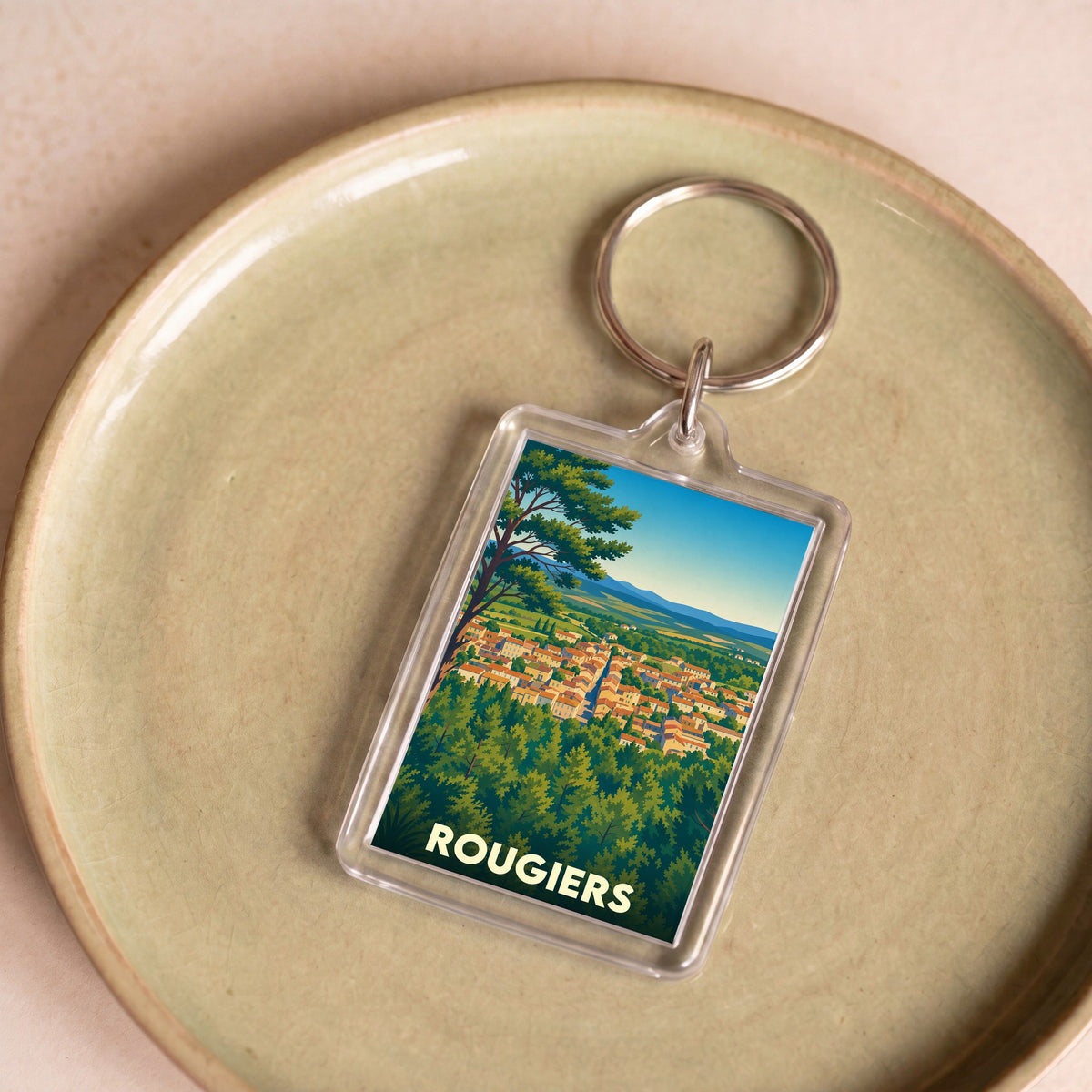 Porte-clés souvenir de la ville de Rougiers avec une illustration stylisée d'un village provençal.