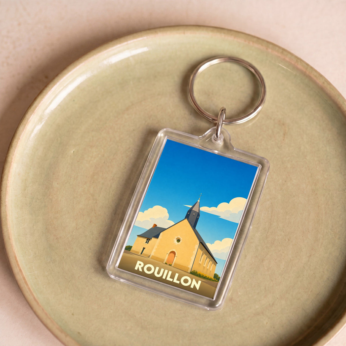 Porte-clés souvenir de la ville de Rouillon avec une illustration stylisée de son église.