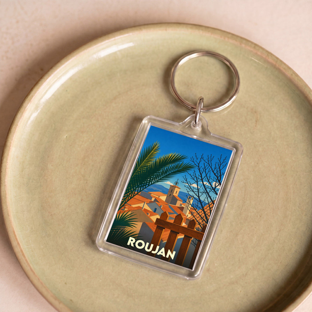 Porte-clés souvenir de la ville de Roujan avec une illustration stylisée.