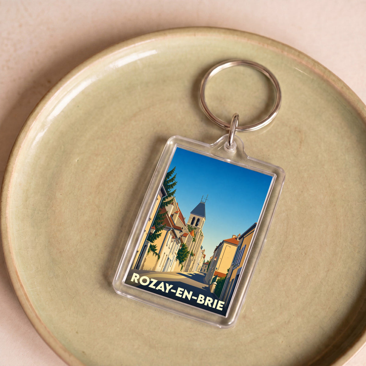 Porte-clés souvenir de la ville de Rozay-en-Brie avec une illustration stylisée d'une rue historique.