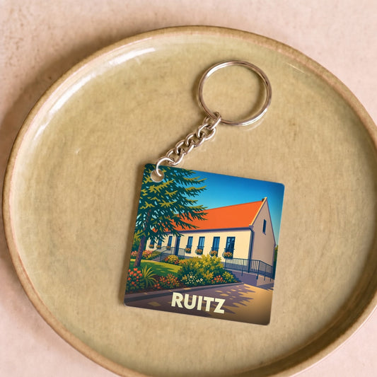 Porte-clés souvenir de la ville de Ruitz avec une illustration stylisée d'un bâtiment fleuri.