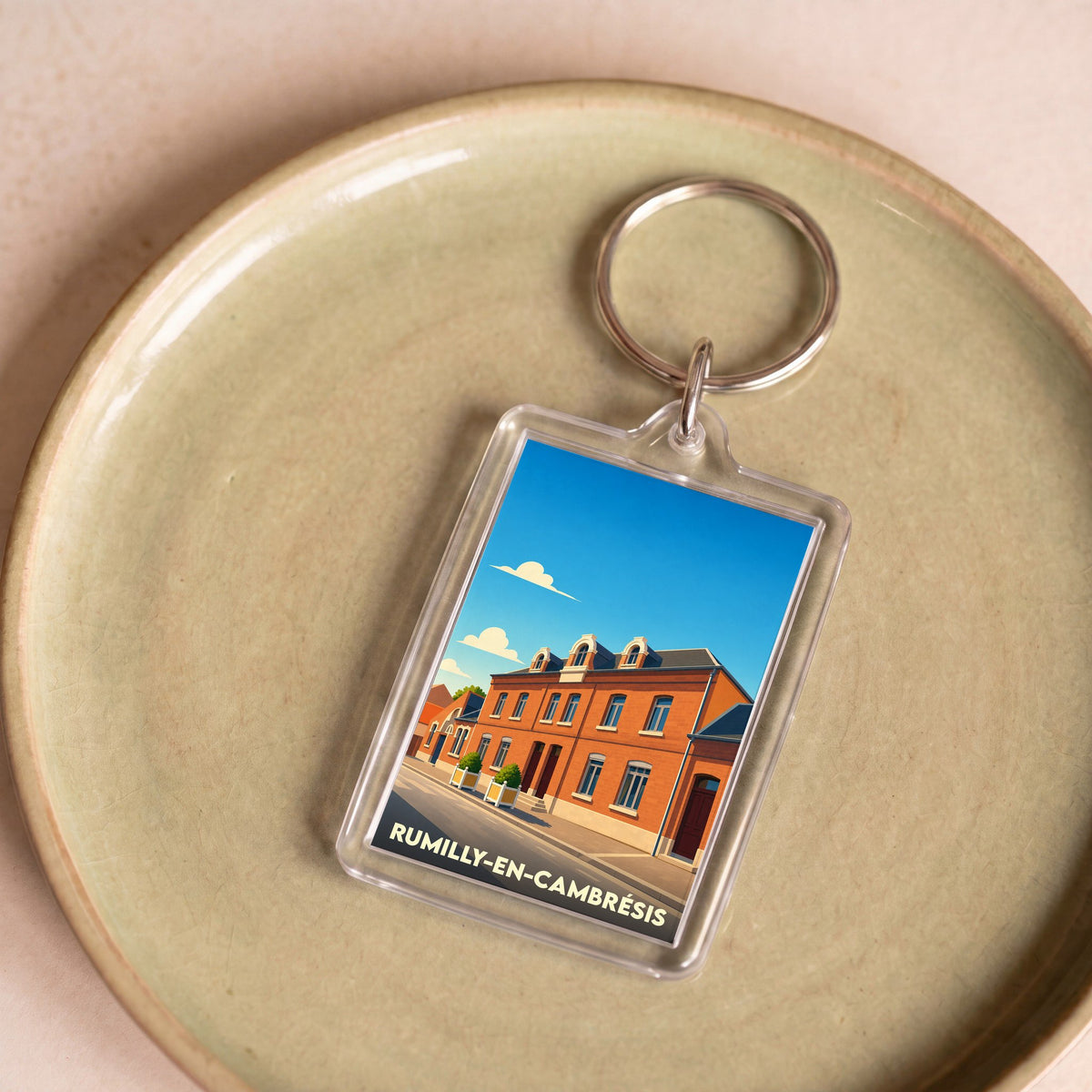 Porte-clés souvenir de la ville de Rumilly-en-Cambrésis avec une illustration stylisée.
