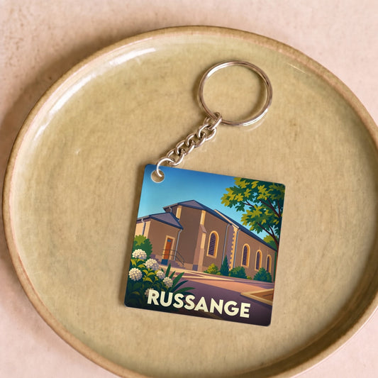 Porte-clés souvenir de la ville de Russange avec une illustration stylisée de son église.