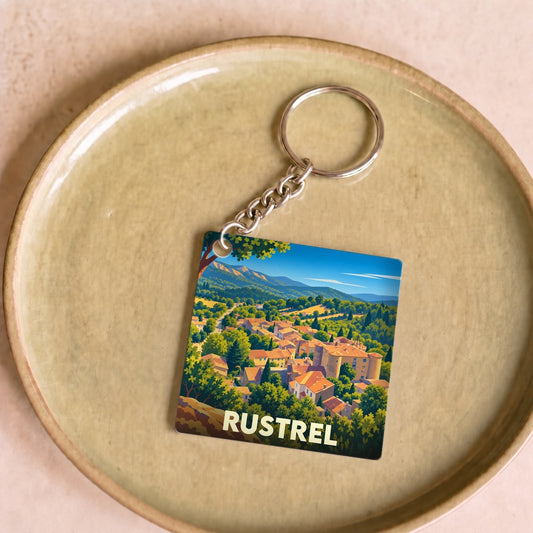 Porte-clés souvenir de la ville de Rustrel avec une illustration stylisée d'un village provençal.