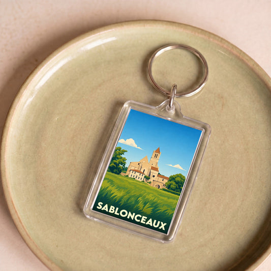 Porte-clés souvenir de la ville de Sablonceaux avec une illustration stylisée de son abbaye.