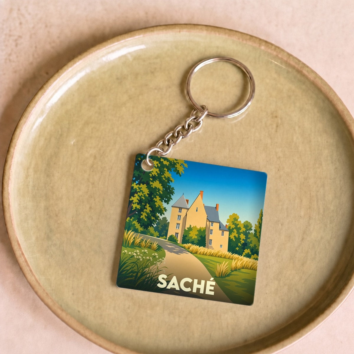 Porte-clés souvenir de la ville de Saché avec une illustration stylisée d'un château.