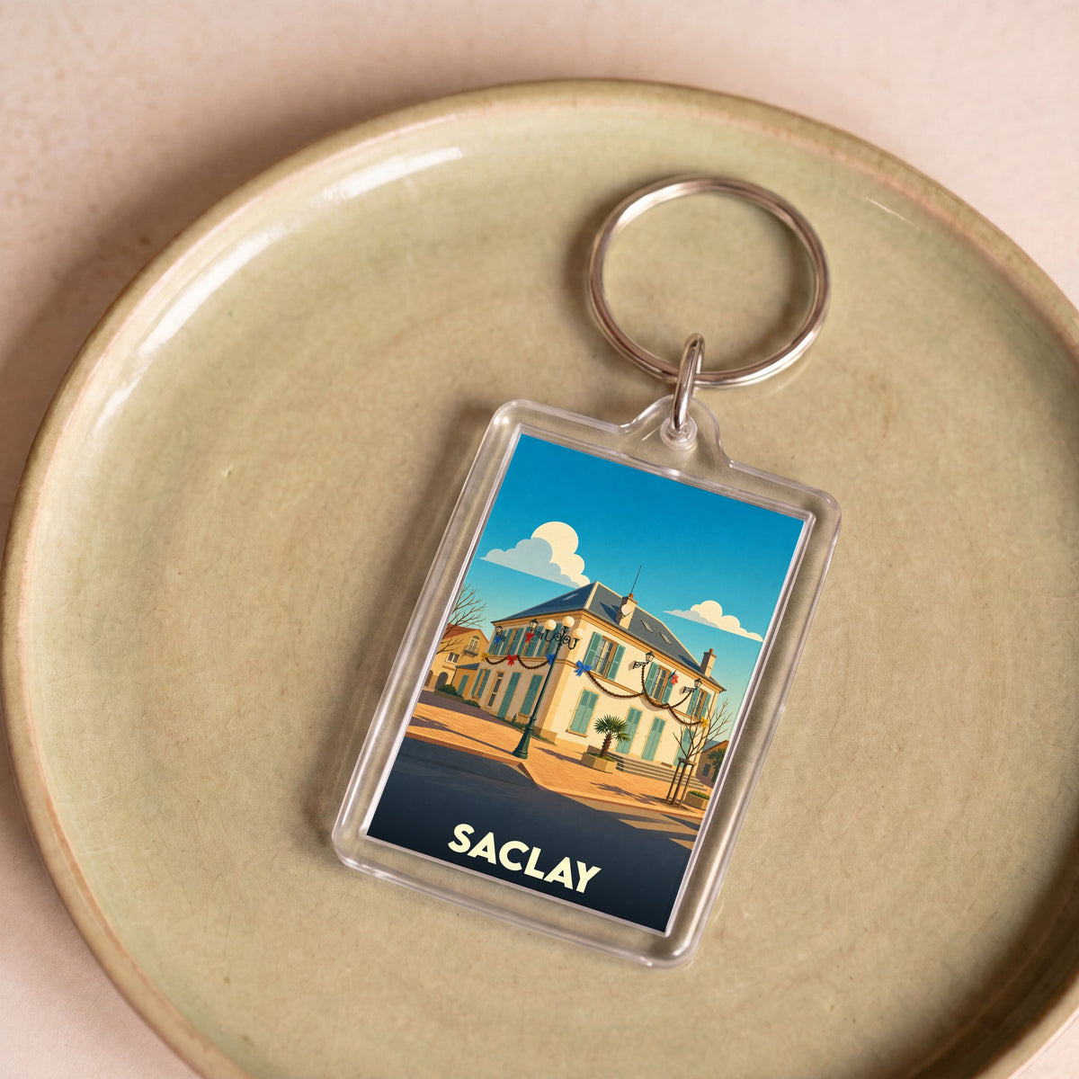 Porte-clés souvenir de la ville de Saclay avec une illustration stylisée d'un bâtiment emblématique.