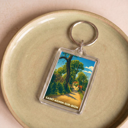 Porte-clés souvenir de la ville de Saint-Agnin-sur-Bion avec une illustration de chemin arboré.