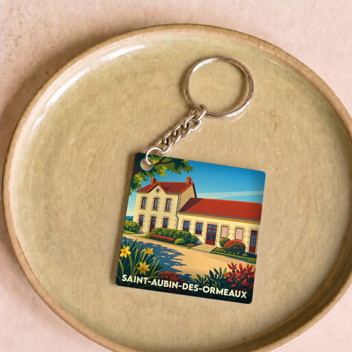 Porte-clés souvenir de la ville de Saint-Aubin-des-Ormeaux avec une illustration stylisée.