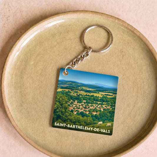 Porte-clés souvenir de la ville de Saint-Barthélemy-de-Vals avec une illustration stylisée du village et de sa campagne.