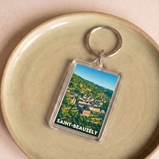Porte-clés souvenir de la ville de Saint-Beauzély avec une illustration stylisée du village niché dans les collines.