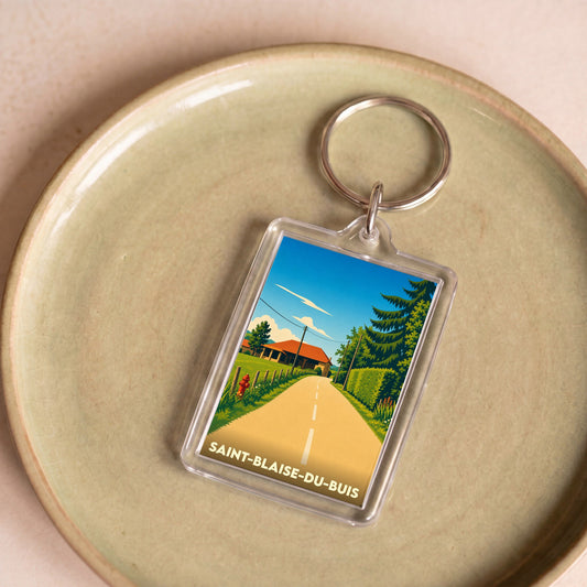 Porte-clés souvenir de la ville de Saint-Blaise-du-Buis avec une illustration stylisée d'un paysage rural.