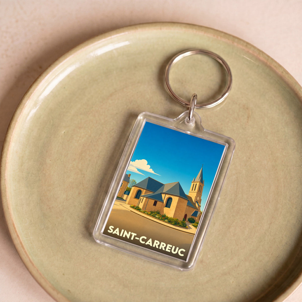 Porte-clés souvenir de la ville de Saint-Carreuc avec une illustration stylisée de son église.