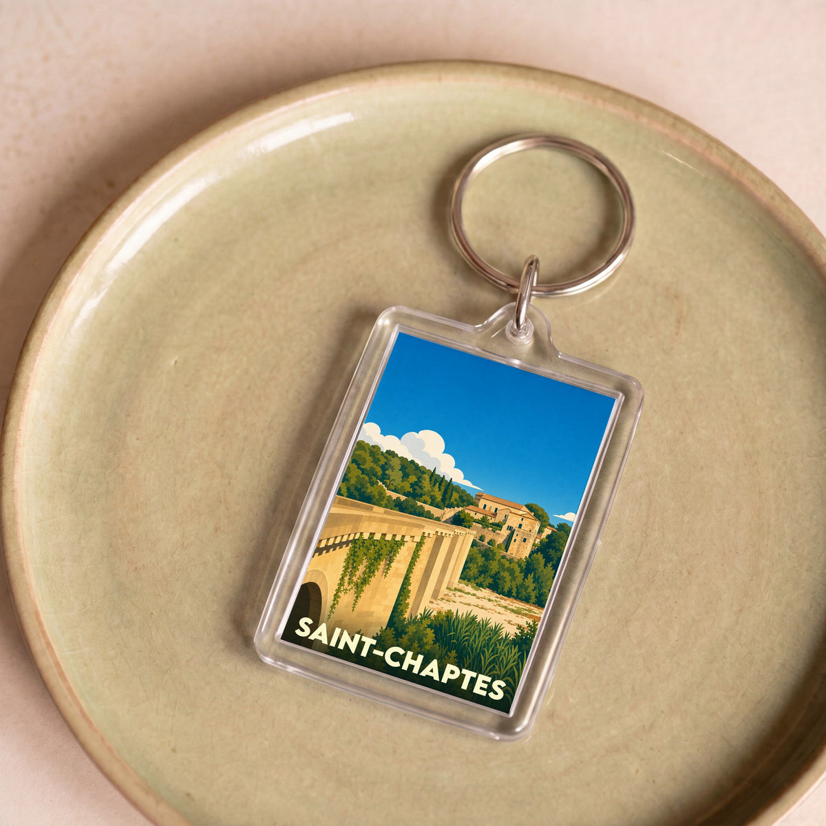 Porte-clés souvenir de la ville de Saint-Chaptes avec une illustration stylisée.