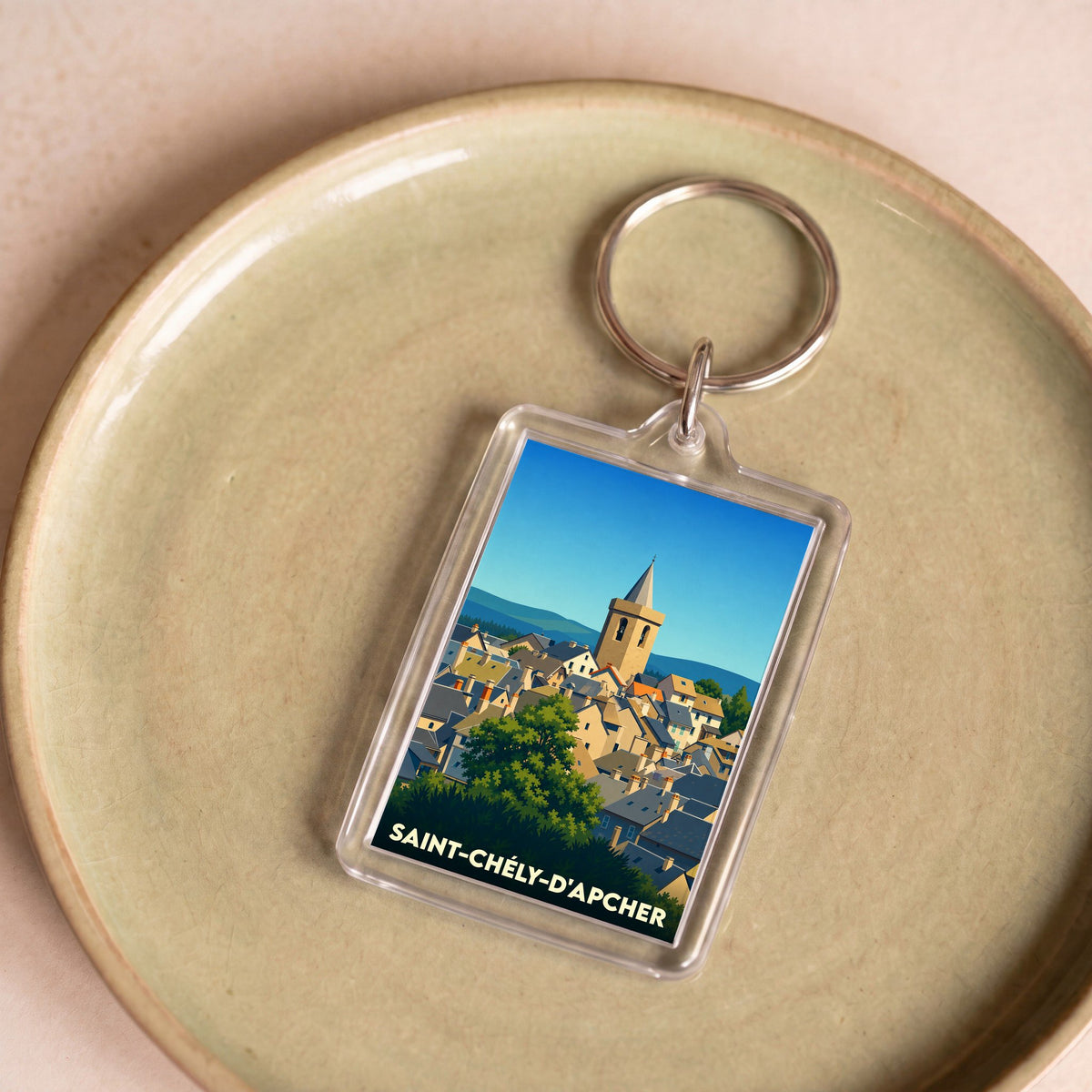 Porte-clés souvenir de la ville de Saint-Chély-d'Apcher avec une illustration stylisée.
