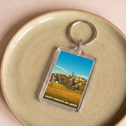 Porte-clés souvenir de la ville de Saint-Christo-en-Jarez avec une illustration stylisée du village.
