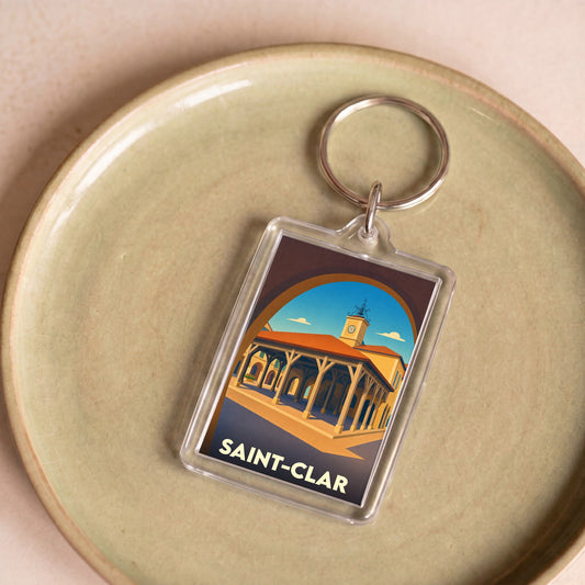 Porte-clés souvenir de la ville de Saint-Clar avec une illustration stylisée de sa halle médiévale.