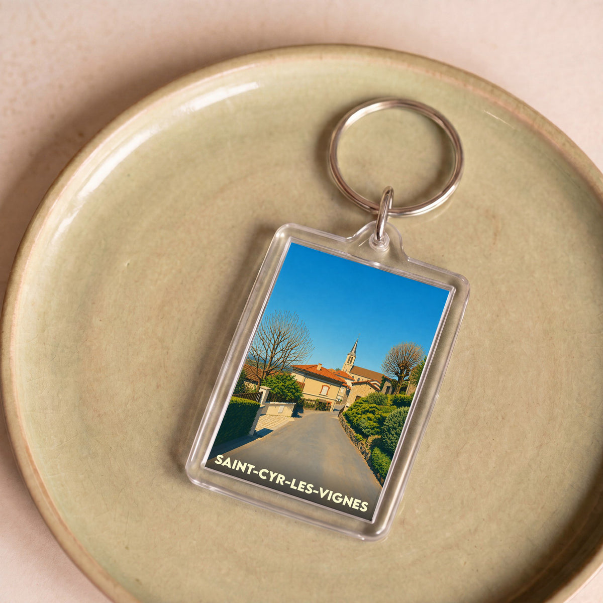 Porte-clés souvenir de la ville de Saint-Cyr-les-Vignes avec une illustration stylisée du village.
