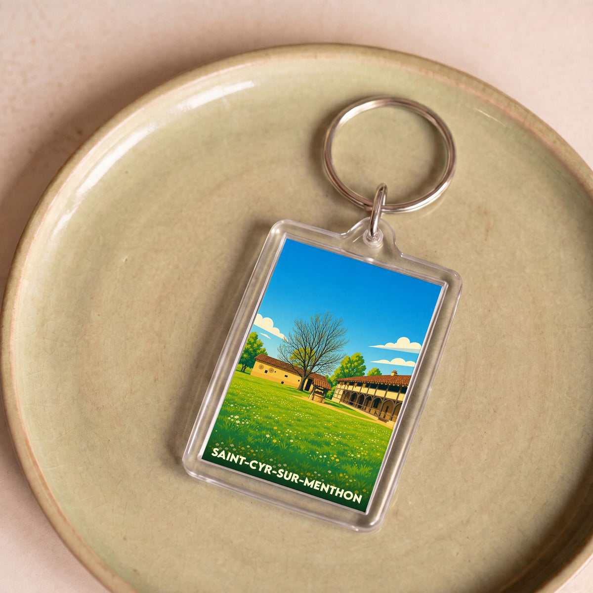 Porte-clés souvenir de Saint-Cyr-sur-Menthon avec une illustration stylisée de son patrimoine rural.