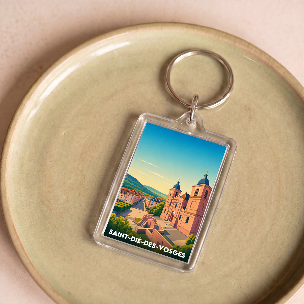Porte-clés souvenir de la ville de Saint-Dié-des-Vosges avec une illustration stylisée.