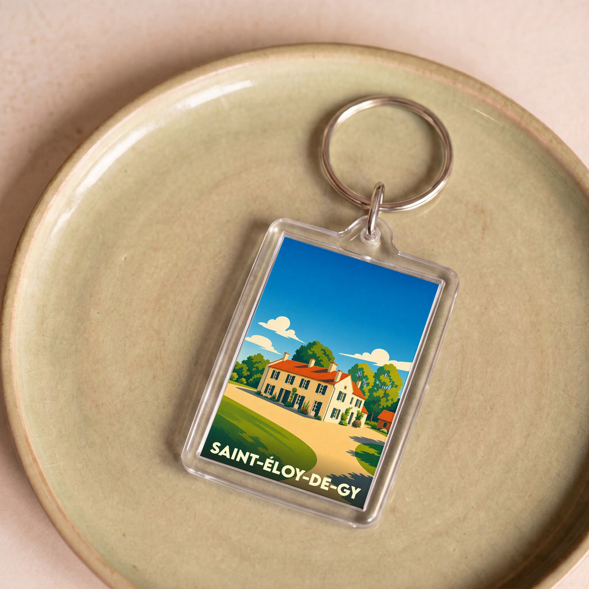 Porte-clés souvenir de la ville de Saint-Éloy-de-Gy avec une illustration stylisée d'une maison de campagne.