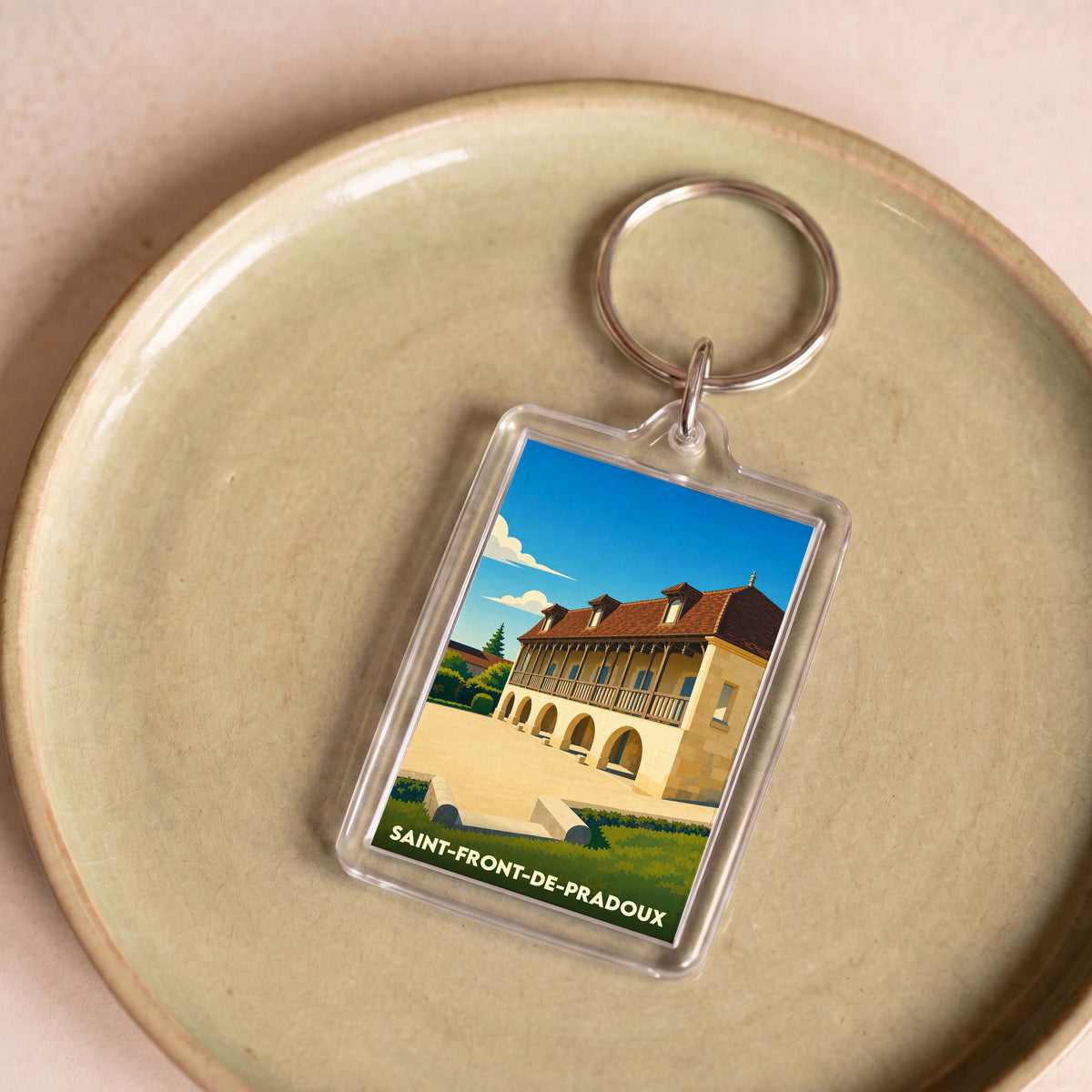 Porte-clés souvenir de Saint-Front-de-Pradoux avec une illustration stylisée de son patrimoine architectural.