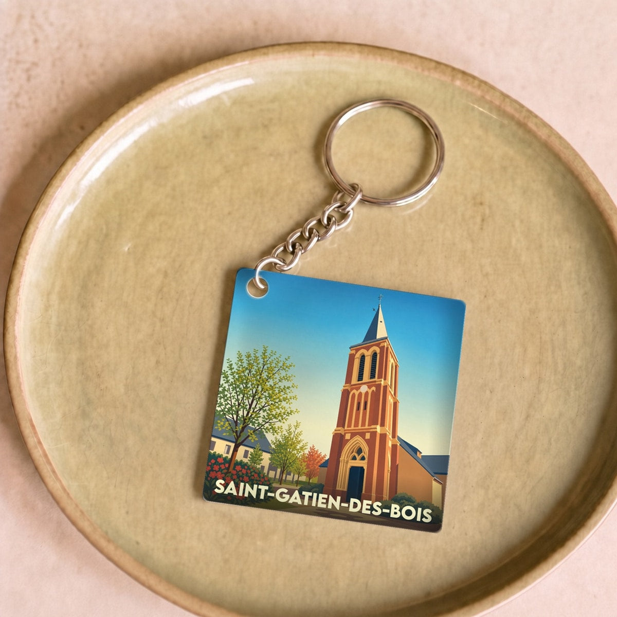 Porte-clés souvenir de la ville de Saint-Gatien-des-Bois avec une illustration stylisée de son église.