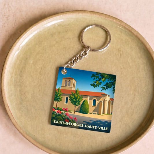 Porte-clés souvenir de Saint-Georges-Haute-Ville avec une illustration stylisée de son église sous un ciel bleu.