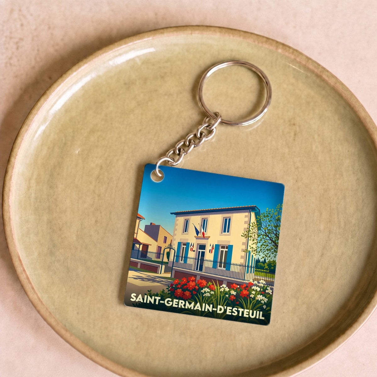 Porte-clés souvenir de la ville de Saint-Germain-d'Esteuil avec une illustration stylisée de sa mairie fleurie.