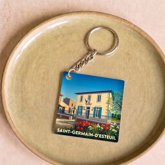 Porte-clés souvenir de la ville de Saint-Germain-d'Esteuil avec une illustration stylisée de sa mairie fleurie.
