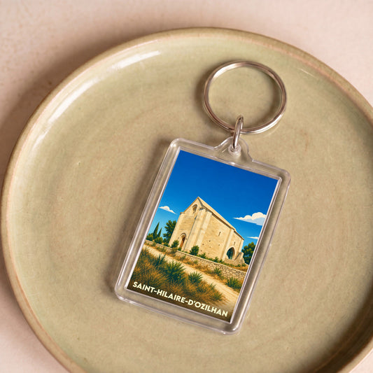 Porte-clés souvenir de la ville de Saint-Hilaire-d'Ozilhan avec une illustration stylisée de sa chapelle romane.