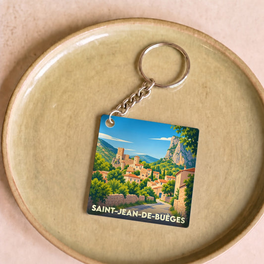 Porte-clés souvenir de la ville de Saint-Jean-de-Buèges avec une illustration stylisée du village et de son château.