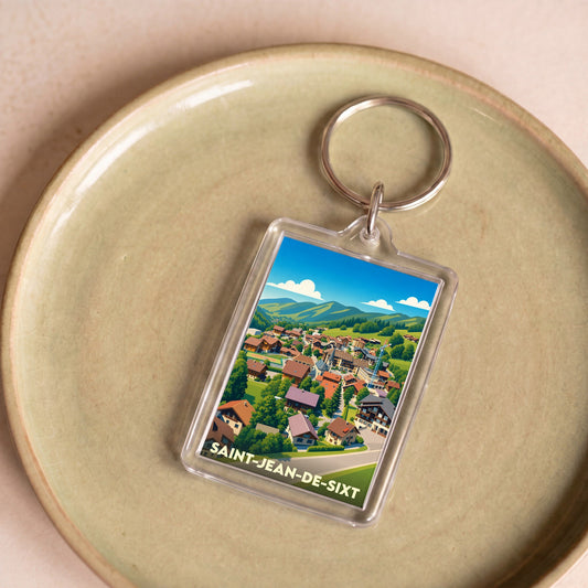 Porte-clés souvenir de la ville de Saint-Jean-de-Sixt avec une illustration stylisée d'un village de montagne.
