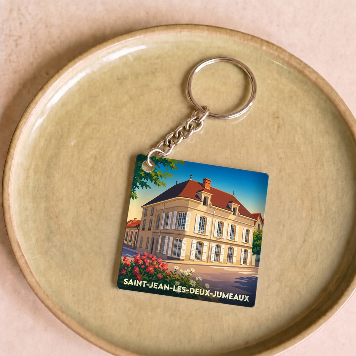 Porte-clés souvenir de la ville de Saint-Jean-les-Deux-Jumeaux avec une illustration stylisée.