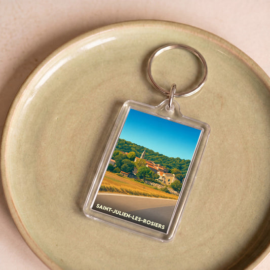 Porte-clés souvenir de Saint-Julien-les-Rosiers avec une illustration stylisée du village et de ses paysages.