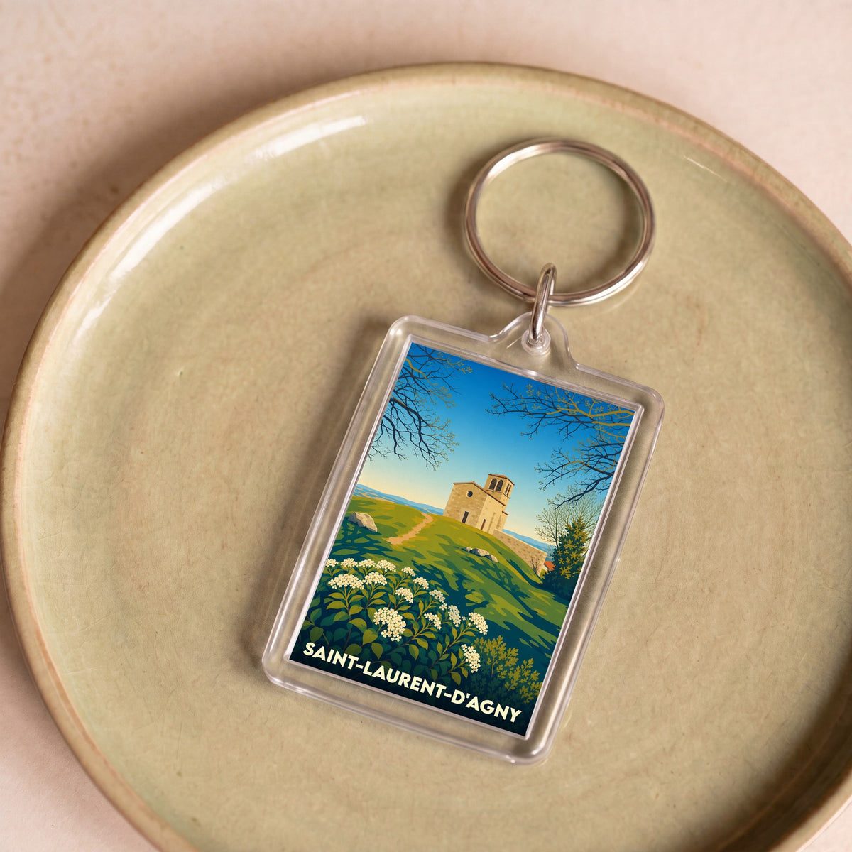 Porte-clés souvenir de la ville de Saint-Laurent-d'Agny avec une illustration stylisée d'un paysage local.