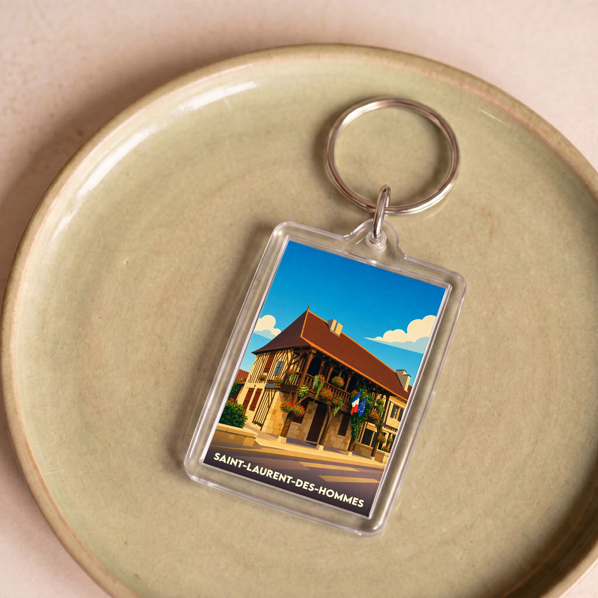 Porte-clés souvenir de la ville de Saint-Laurent-des-Hommes avec une illustration stylisée.